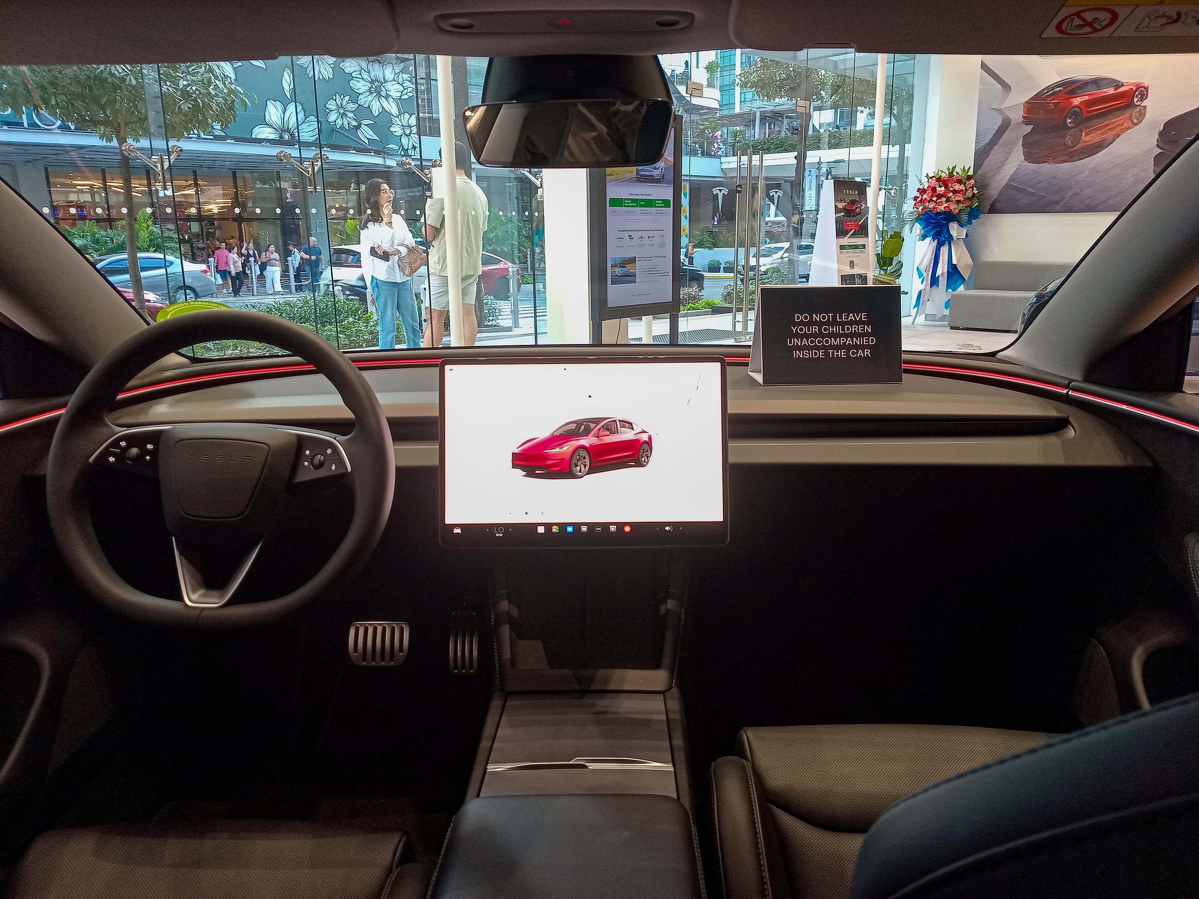 2024 Tesla Model 3 Highland interior — yoke-free wheel, widescreen, ambient light bar